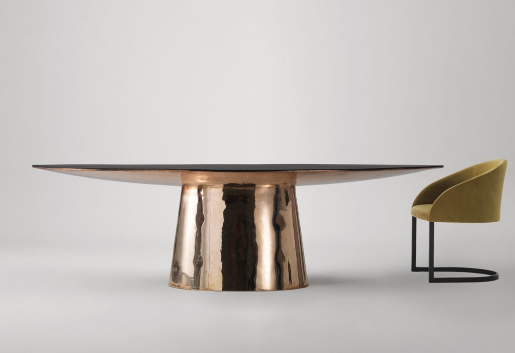 oval table made on a wooden base and lightly covered with leather and veneer in a golden colour tone