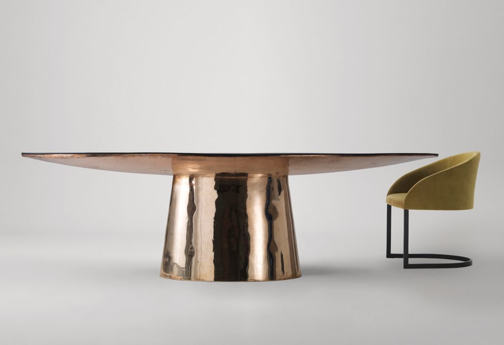 oval table made on a wooden base and lightly covered with leather and veneer in a golden colour tone