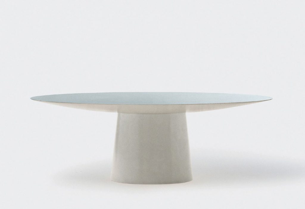 oval table made on a wooden base and lightly covered with leather and veneer in a white colour tone on a white background