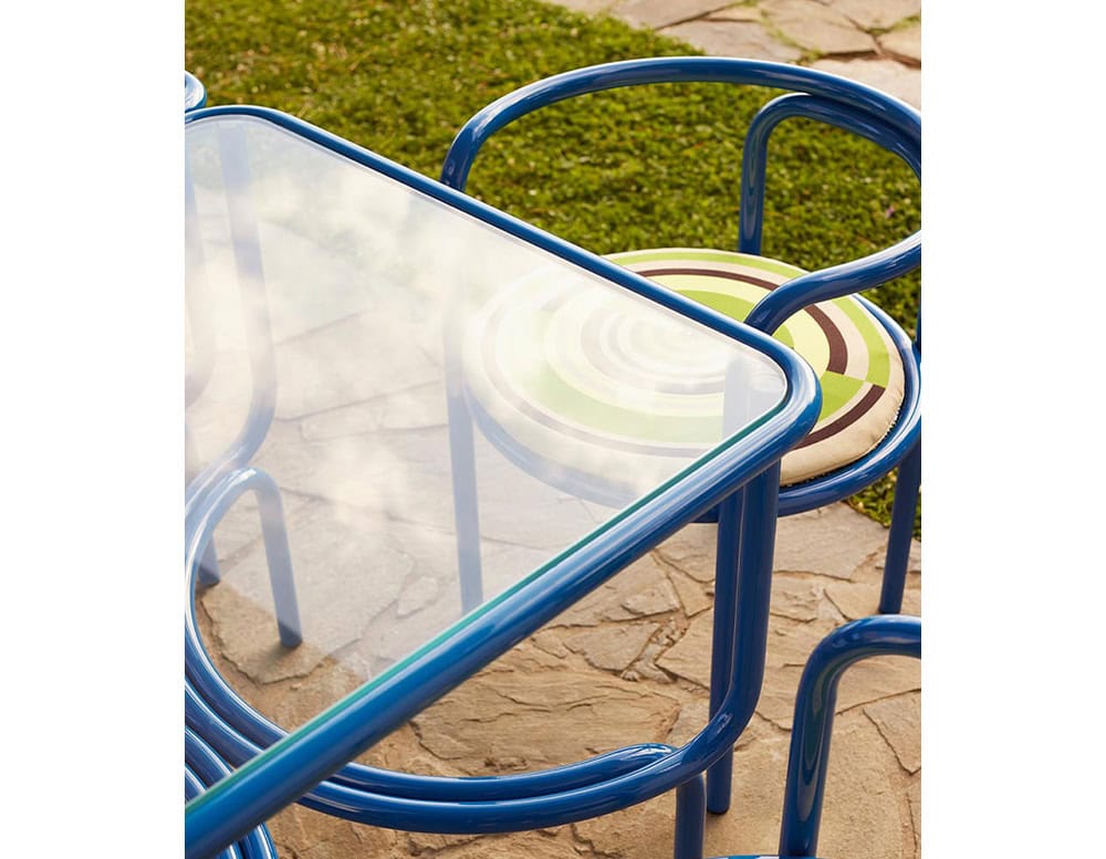 Locus Solus Chair with armrest. Struture in blue metal and multicolored cushion on a terrace.