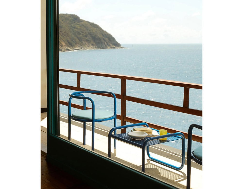 Two Locus Solus Chairs with armrest. Struture in blue metal and cushion on a terrace.