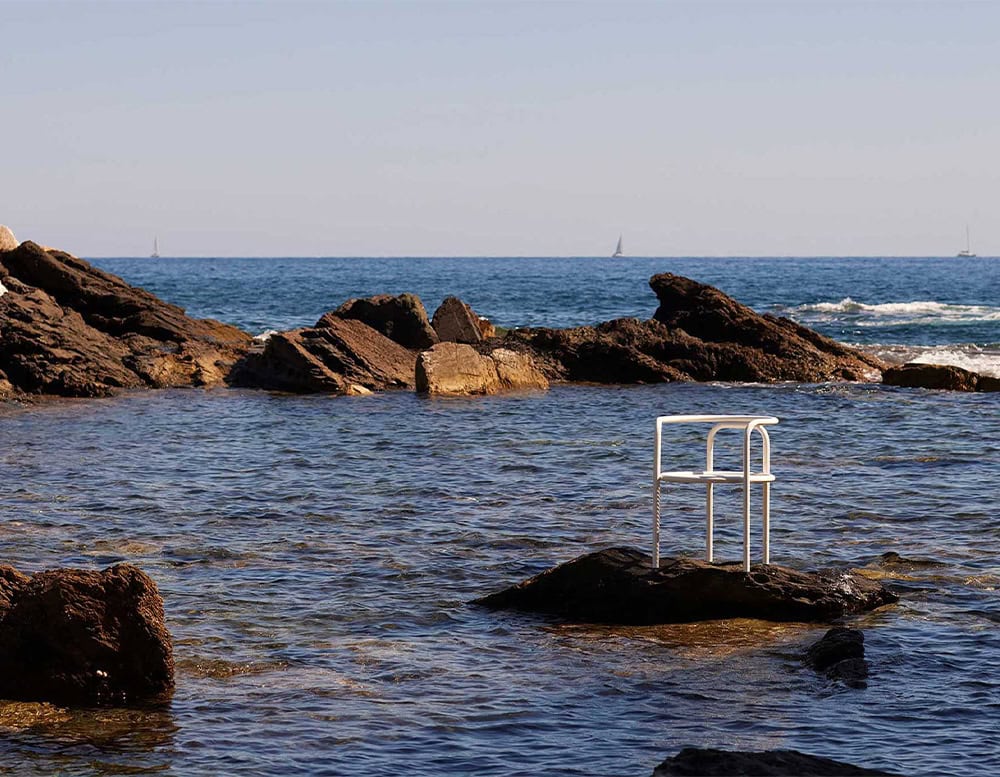 Locus Solus Chair with armrest. Structure in white metal on the ocean.