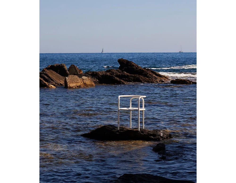 Locus Solus Chair with armrest. Structure in white metal on the ocean.