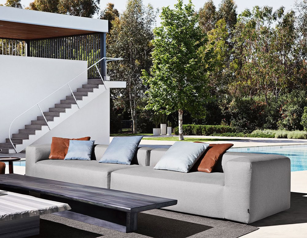 Two Montecarlo Lounge sofas with backrest and armrest in gray fabric with pillows on a terrace.