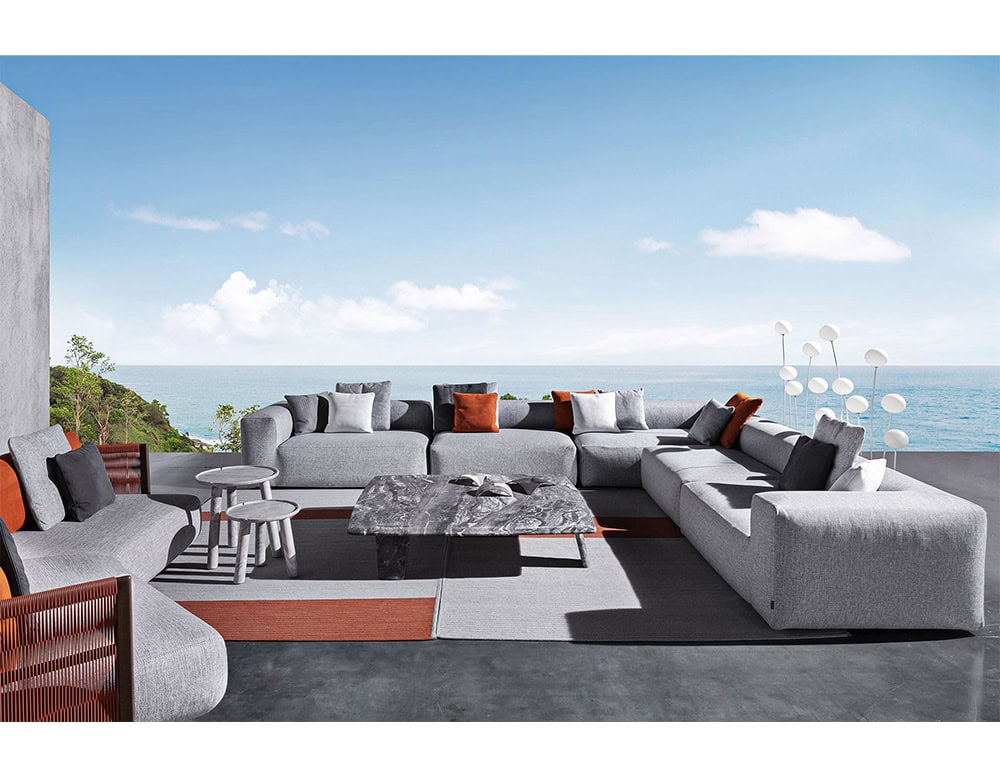 Two Montecarlo Lounge sofas with backrest and armrest in gray fabric with pillows in a living room.