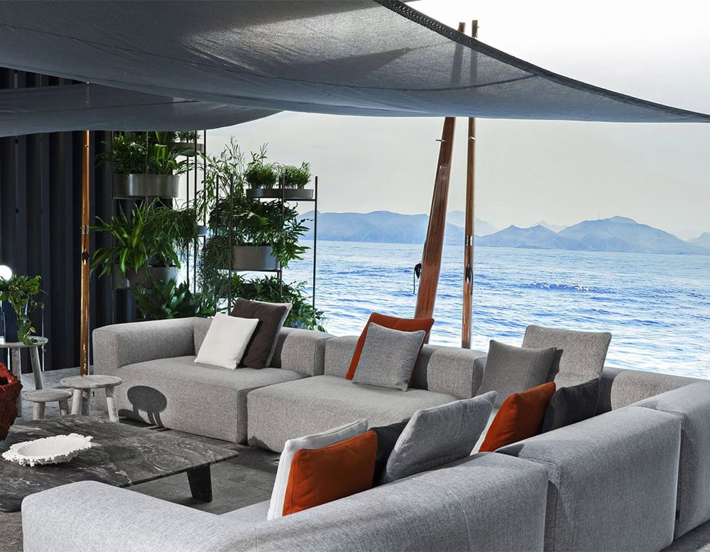 Two Montecarlo Lounge sofas with backrest and armrest in gray fabric with pillows in a living room.