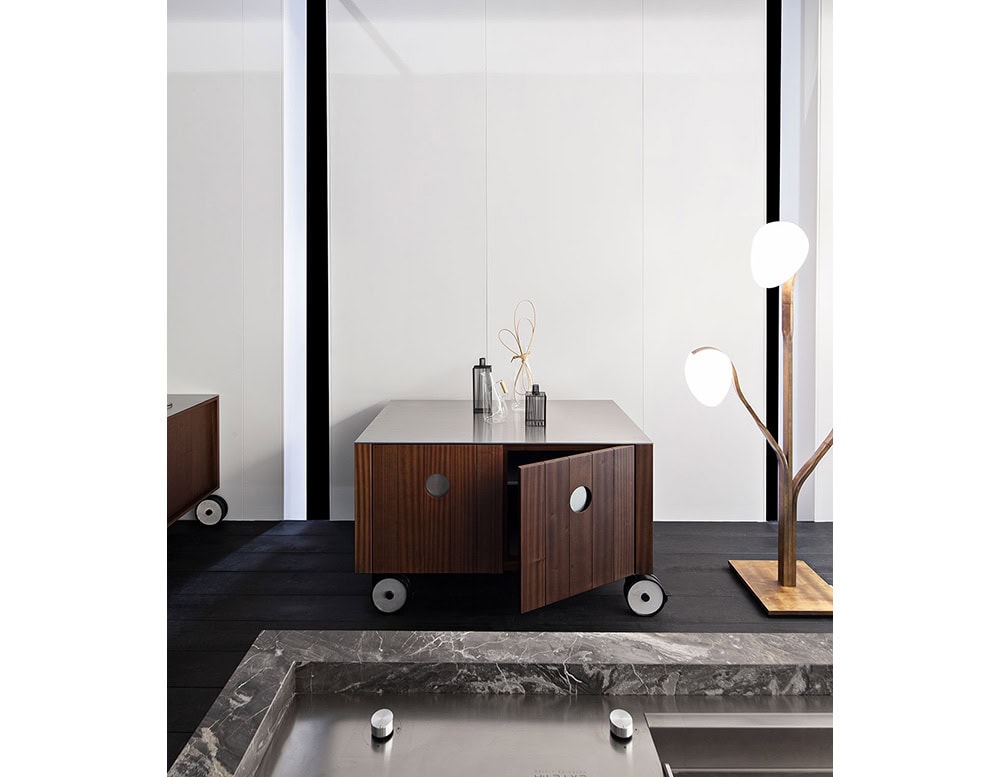 Roller Kitchen cabin covered in brown wooden with four wheels against a wall.