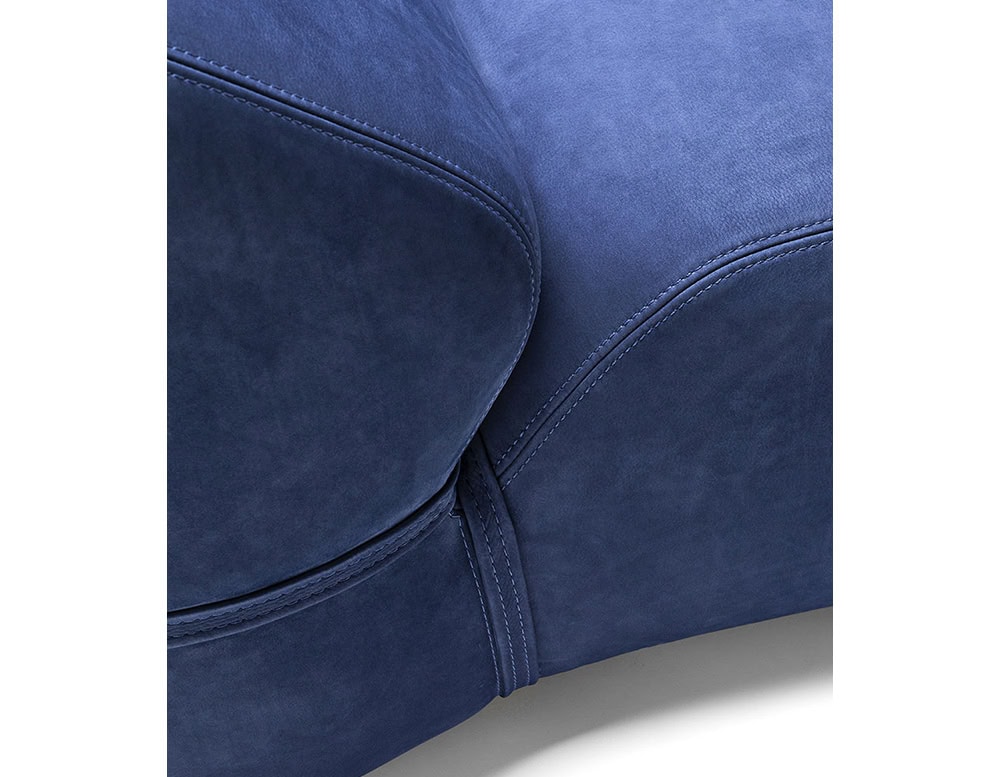 Closeup of Soft Chaise Long covered in blue fabric on a white background.