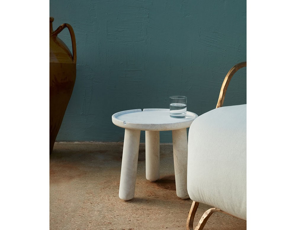 White Stone Round Coffee table in white with three legs in a living room.