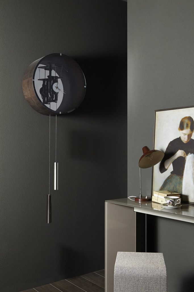 Black Tic Tac 14 pendulum clock with a sleek design, featuring a round face and slender pendulum in a living room.