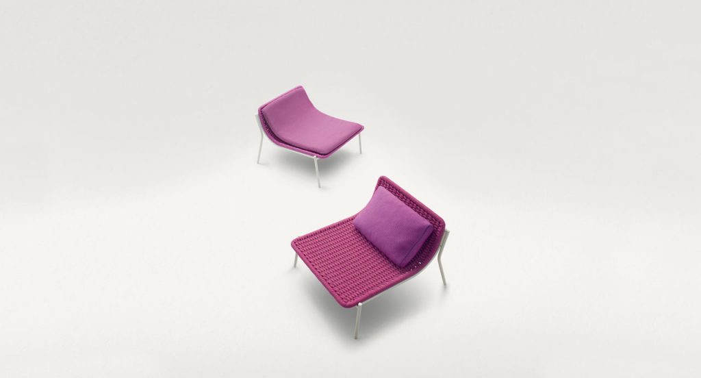 Two pink Baia lounge chairs, four legs in white steel, structure upholstery in fabric, left with seat pad and right with cushion on a white background.