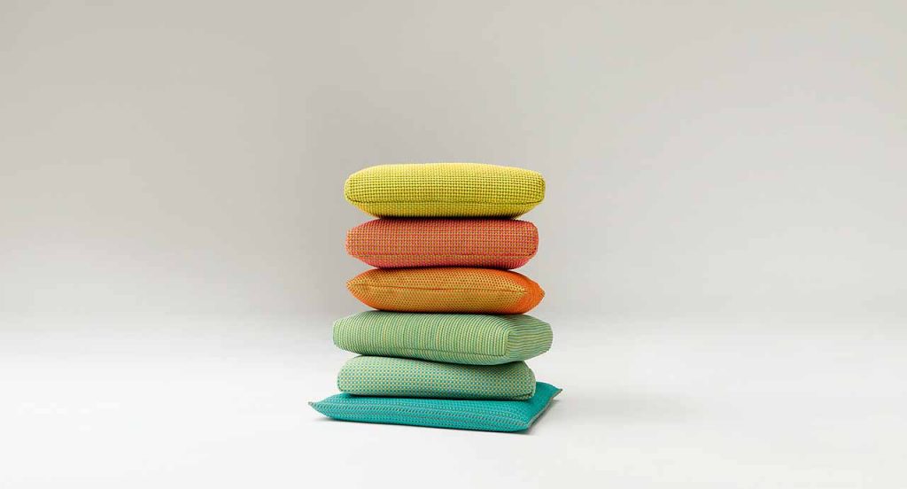 Six Indoor Cushions, upholstery, one in blue, two in green, one in orange, one in red and one in yellow on a white background.