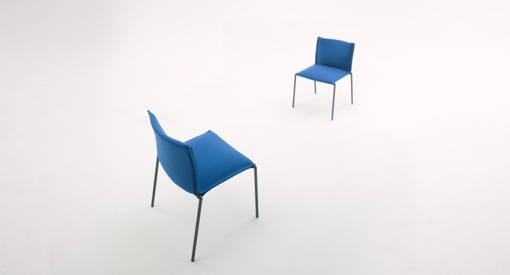 Two Mae chair, structure and legs of black steel, upholstery in blue fabric on a white background.