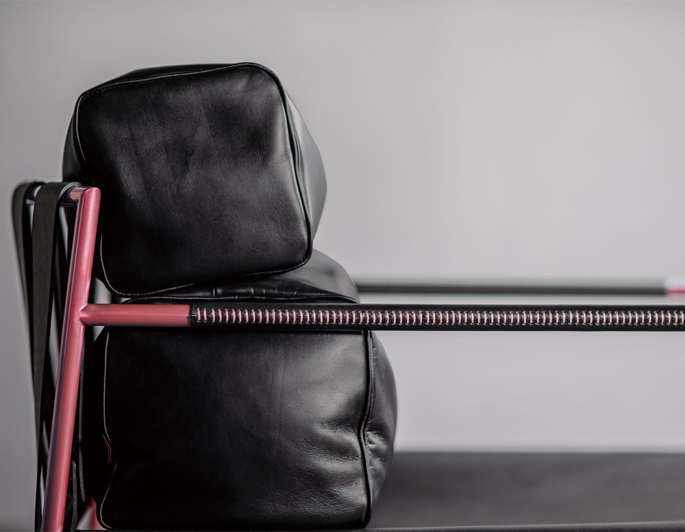 Armchair with base made of black steel with red finishes on a gray background