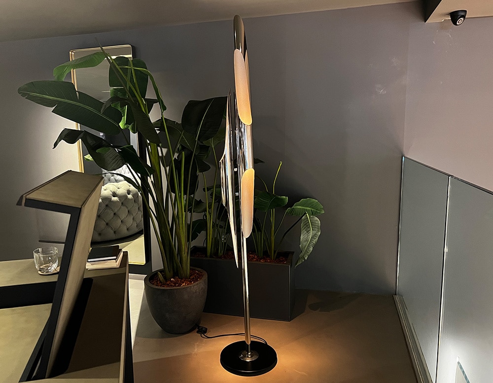 Floor lamp with 3 lampshades made of aluminum and brass, finished in matte black and gold paint in a living room.