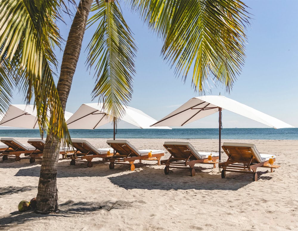 two umbrellas made of silver and white steel in their fabric on a beach in the background