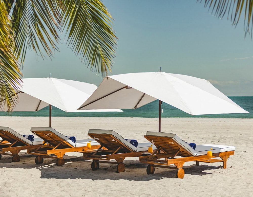 two umbrellas made of silver and white steel in their fabric on a beach in the background