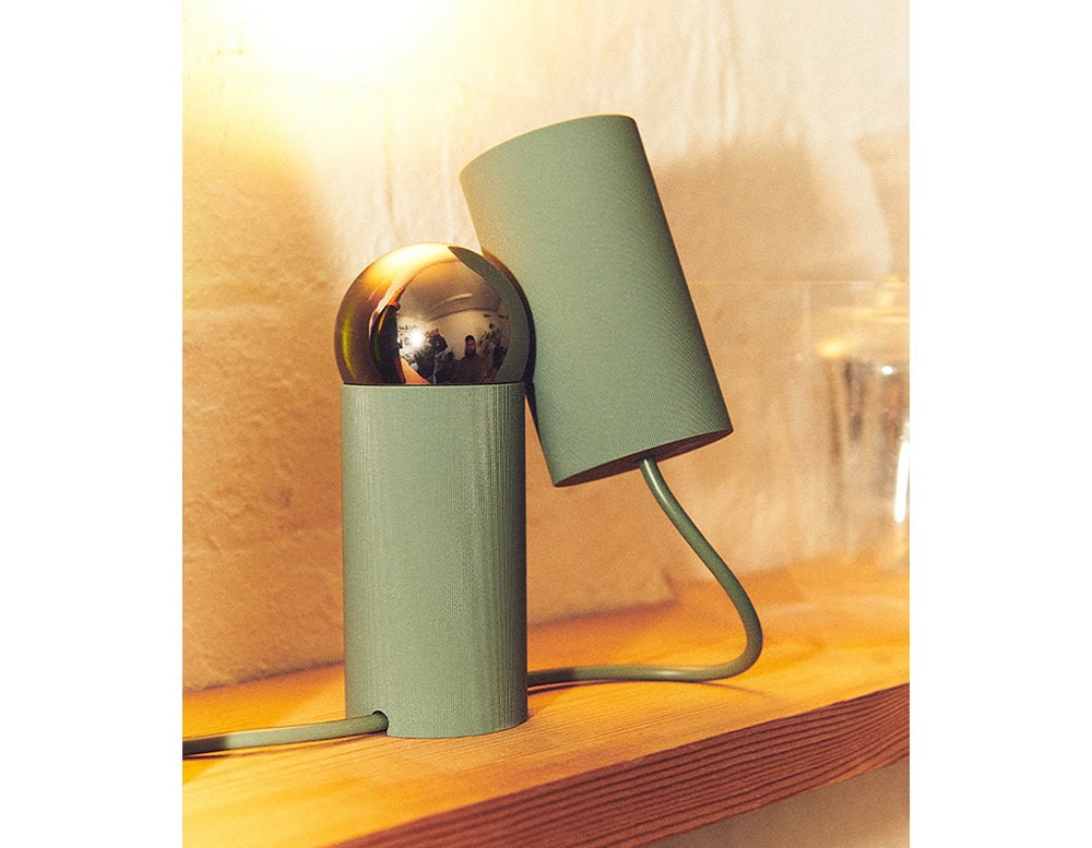 Flos Bilboquet lamp with cylindrical shape in green on a drawer.