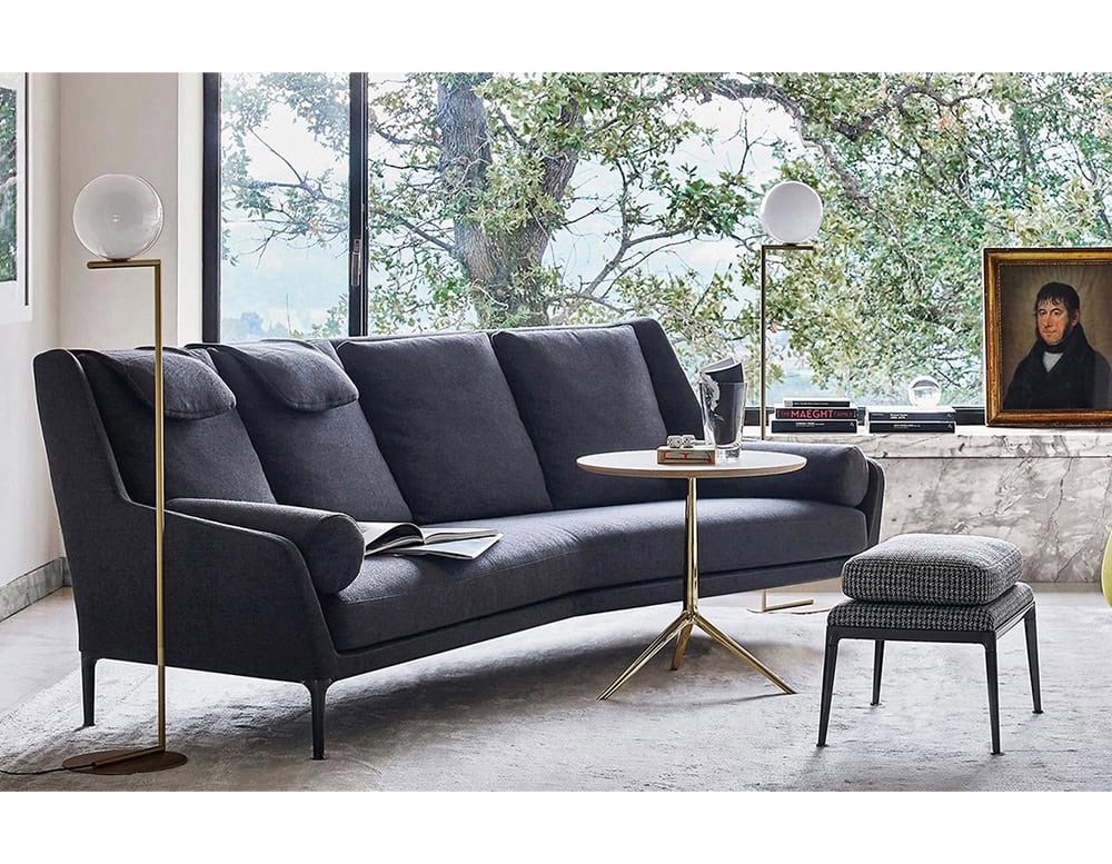 Flos IC floor lamp standing next to a navy colored sofa.