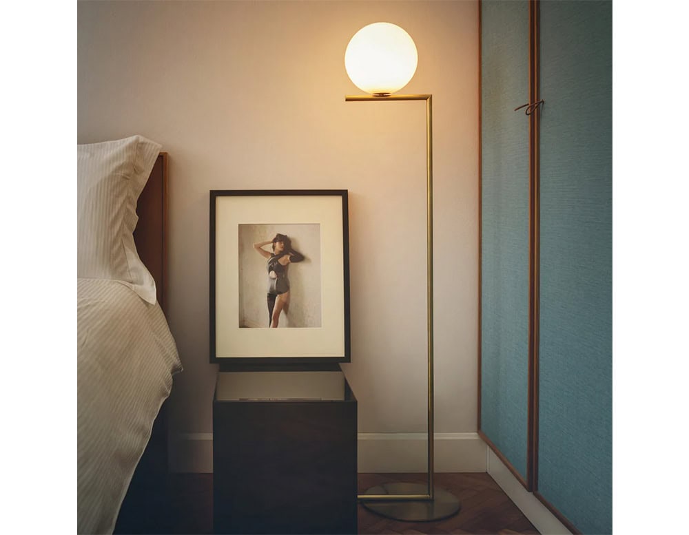 Flos IC Floor Lamp, against a beige wall next to a portrait of a woman