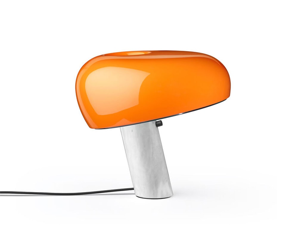 Flos Snoopy lamp. Orange top in head dog like shape and white base on a white background.