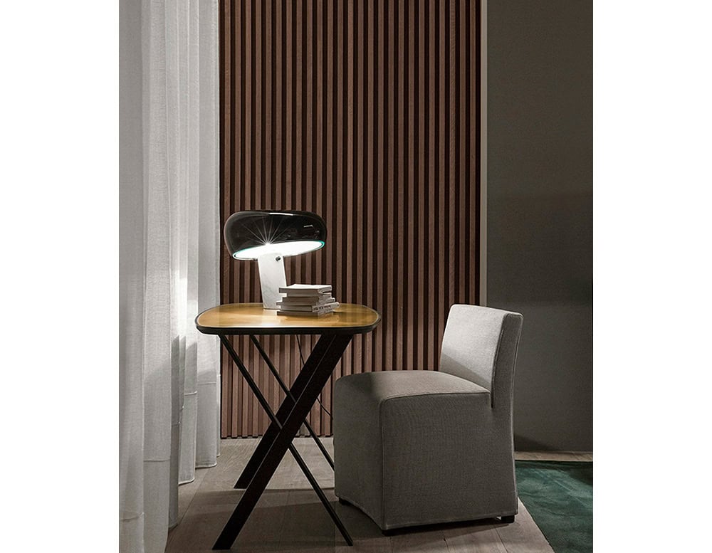 Flos Snoopy table lamp in a dark green shade atop a table and chair set up.