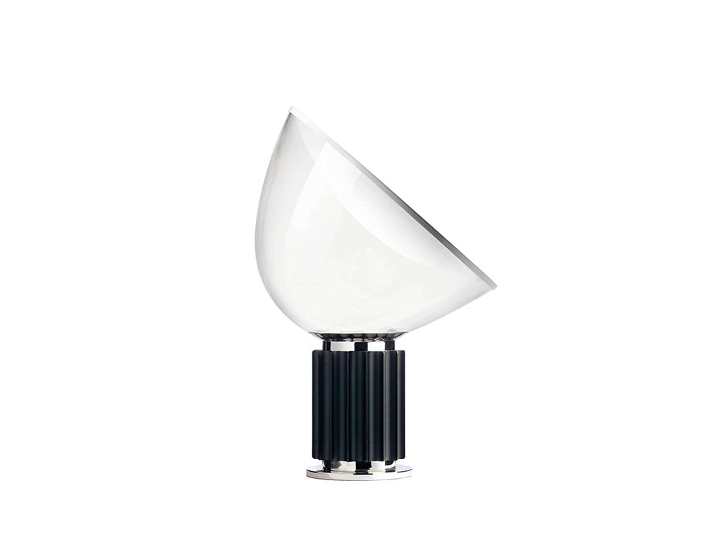 Flos Taccia table lamp with a transparent half circle top and a black oval base on a white background.