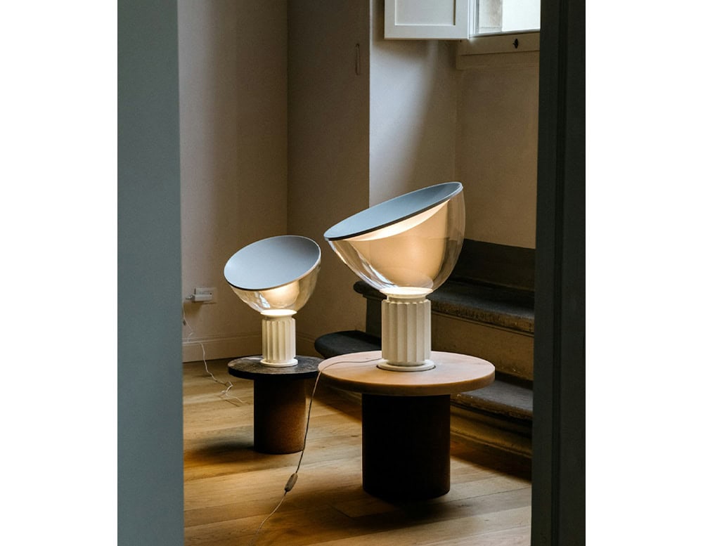 Two Flos Taccia lamps near one another placed on circular marble side tables.