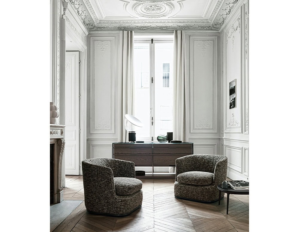 Flos Taccia table lamp on a brown wooden dresser behind two gray chairs.